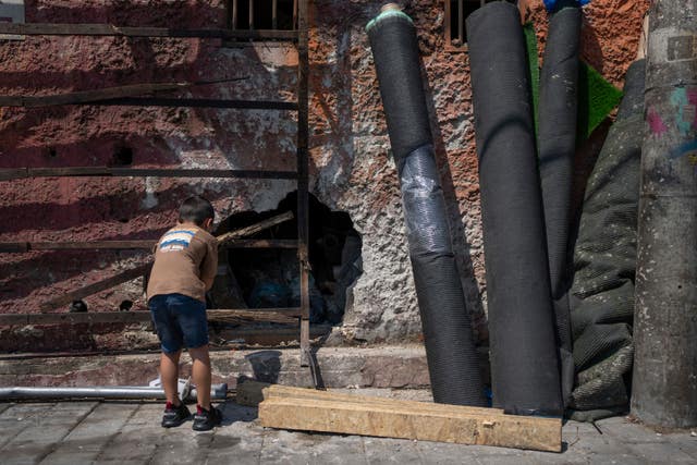 A child looks at at a hole in a wall at the scene of a bomb explosion in Tel Aviv, Israel