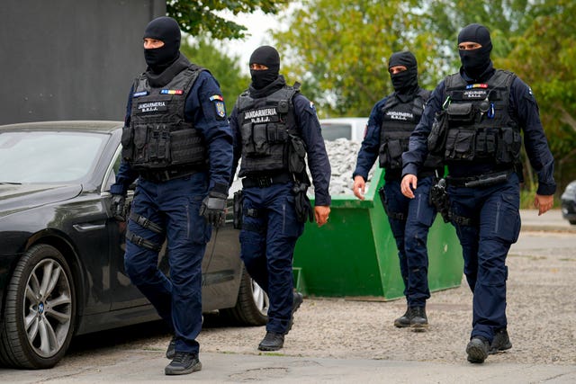 Gendarmes wearing balaclavas walk outside the residence of internet influencer Andrew Tate during an early morning police search raid on the outskirts of Bucharest, Romania