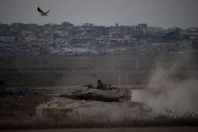 Israeli soldiers move on the top of a tank near the Israeli-Gaza border