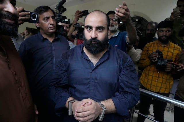 Plainclothes police officers escort Farhan Asif, centre, after his court appearance, in Lahore, Pakistan