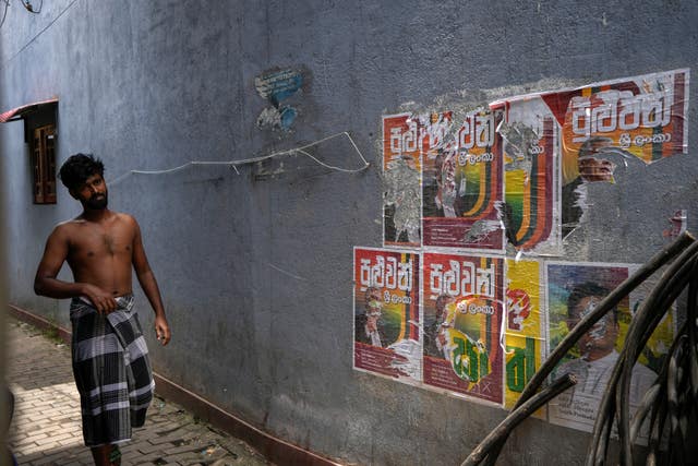 A man walks past old election posters of presidential candidate Ranil Wickremesinghe