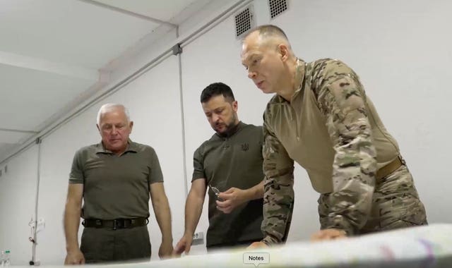 Ukrainian President Volodymyr Zelensky, centre and Commander-in-Chief Oleksandr Syrsky, right, look at a map during their visit to Sumy, Ukraine