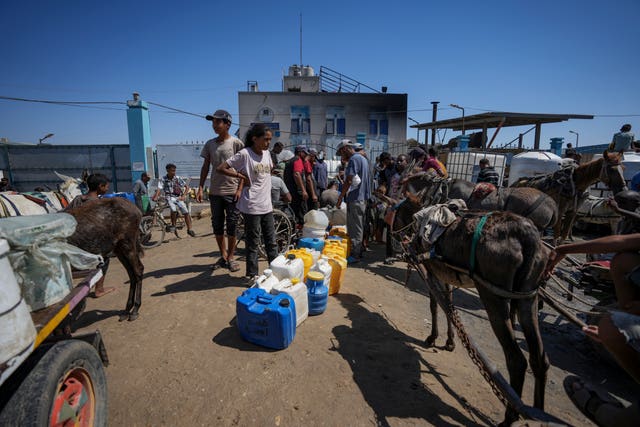 Displaced Palestinians line up to collect water, in Deir al Balah, central Gaza Strip