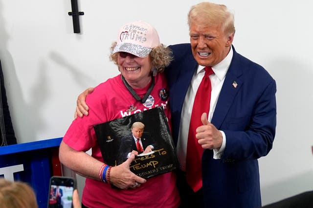 Donald Trump, right, poses with a supporter during a stop at a campaign office