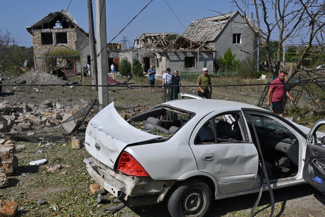 People walk in front of their damaged houses after Russian rocket attack in Usatove village near Odesa 