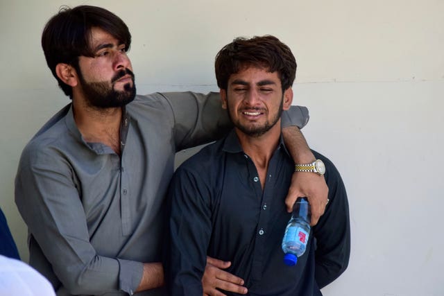 A man comforts another who mourns over the death of a family member killed by gunmen at a highway in Musakhail