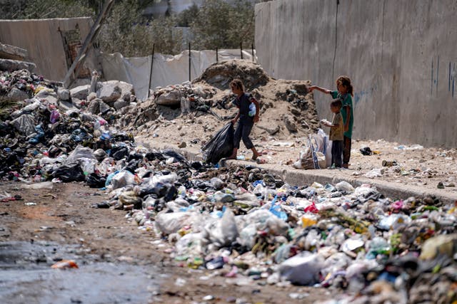 Displaced children sort through trash at a street in Deir al-Balah, central Gaza Strip 