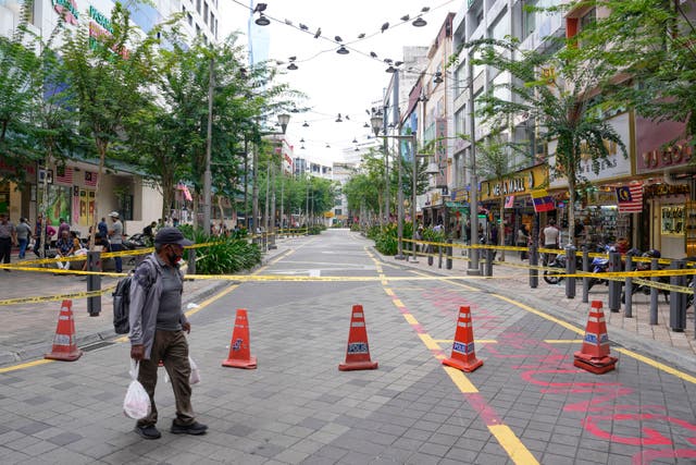 A man crosses a closed roadside after another deep sinkhole appeared a week after a woman fell into a sinkhole when a sidewalk caved in in Kuala Lumpur