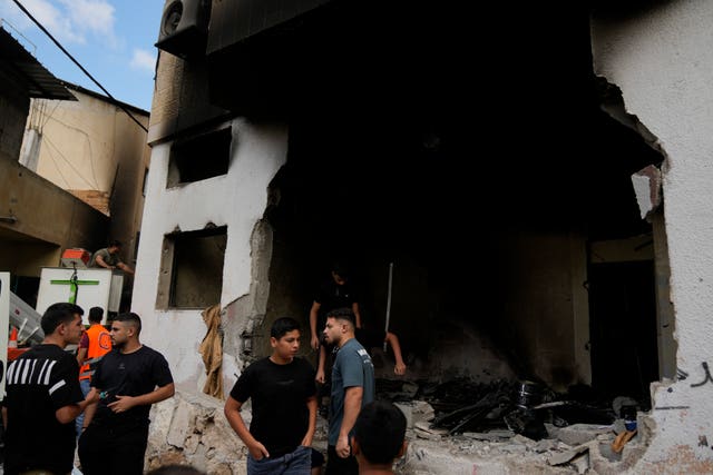 Palestinians stand outside a heavily damaged mosque following an Israeli military operation in the West Bank refugee camp of Al-Faraa