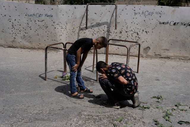 Two boys next to a wall pockmarked by shrapnel 