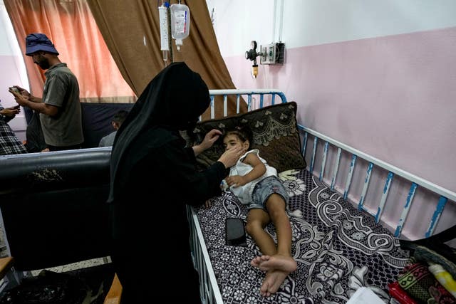 A mother tends to her child, who is lying on a hospital bed