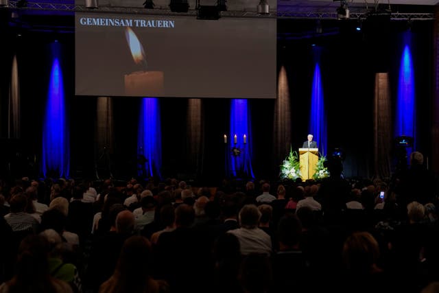 Frank-Walter Steinmeier under spotlight in the distance on a stage, with an audience in the foreground