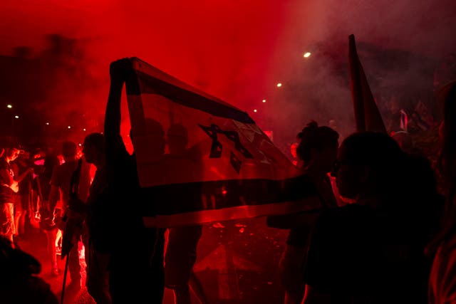 Palestinians demonstrate by the light of a red flare