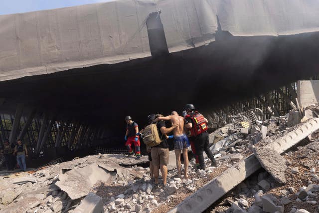 Paramedics help an injured man to walk out of the rubble at a sports facility destroyed after a Russian attack in Kharkiv