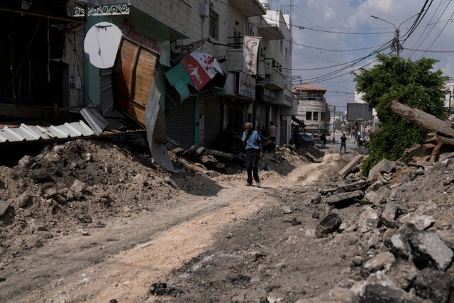 Rubble-stewn street as a man negotiates his way along it