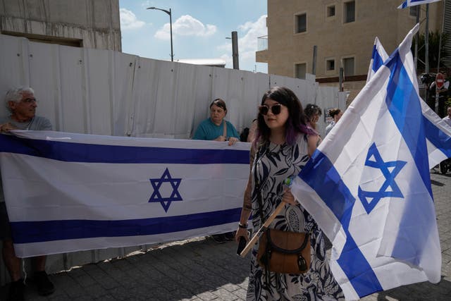 Mourners wave Israeli flags as they accompany the family of Israeli-American hostage Hersh Goldberg-Polin, who was killed in Hamas captivity in the Gaza Strip, on their way to his funeral in Jerusalem