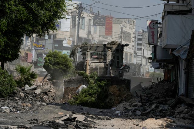 An Israeli military bulldozer tears up a road littered with rubble during an army raid in Jenin, West Bank