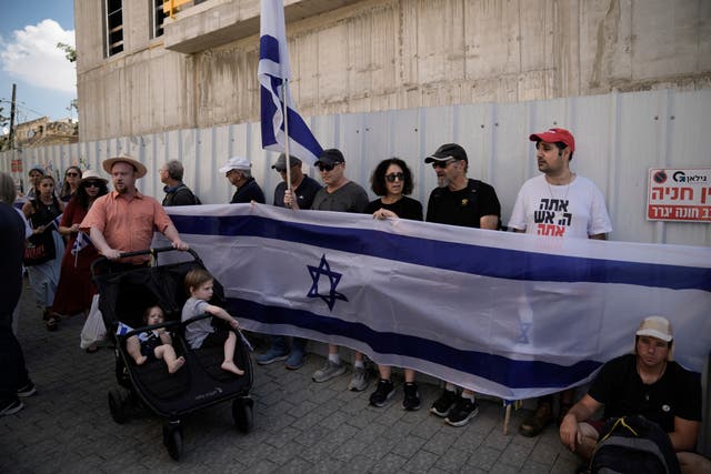 Mourners wave Israeli flags as they accompany the family of Israeli-American hostage Hersh Goldberg-Polin, who was killed in Hamas captivity in the Gaza Strip, on their way to his funeral in Jerusalem 