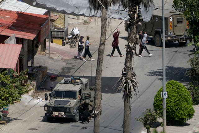 Israeli soldiers arrest a Palestinian man as others walk by with their hands up during a military operation in Jenin, West Bank