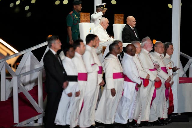 Pope Francis and Papua New Guinea’s deputy prime minister John Rosso sit among attendants