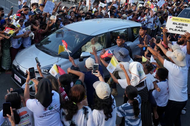 People greet Pope Francis as he travels in a car on the way to the Presidential Palace in Dili, East Timor