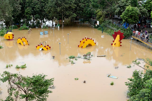 People look on a submerged dragon structure in a playground, following Typhoon Yagi in Hanoi