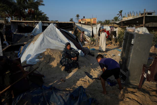 Palestinians look at the destruction after an Israeli air strike on a crowded tent camp housing Palestinians displaced by the war in Muwasi