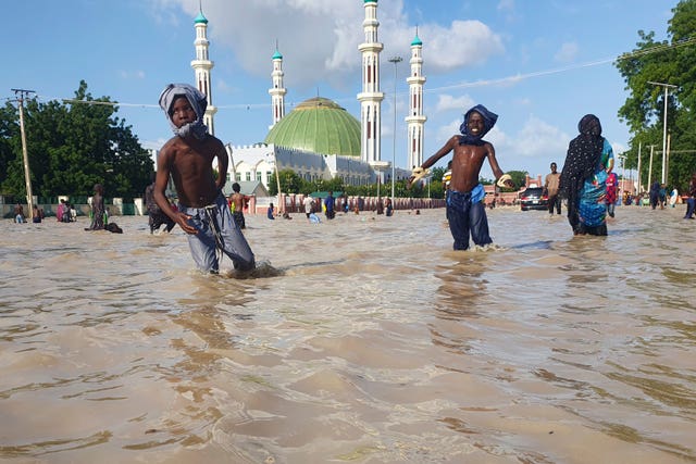 People walk through floodwaters following a dam collapse in Maiduguri, Nigeria