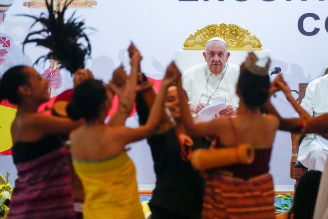 Pope Francis looks at traditional dancers as he arrives in Dili