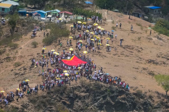 People display a East Timor national flag to show it to Pope Francis taking off with his flight from Díli, East Timor and bound to Singapore