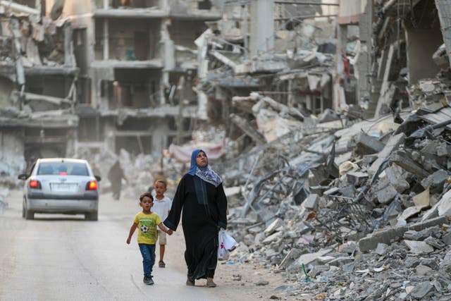 Palestinians walk through destruction left by an Israeli offensive on Khan Younis, Gaza Strip