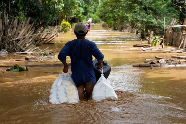 A man carrying food wades through a flooded road 