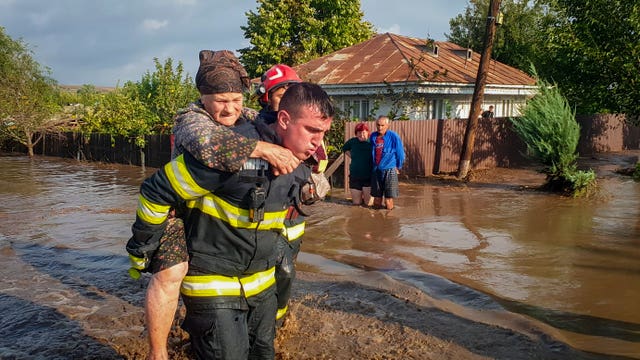 A rescuer carries a woman in Pechea, Romania