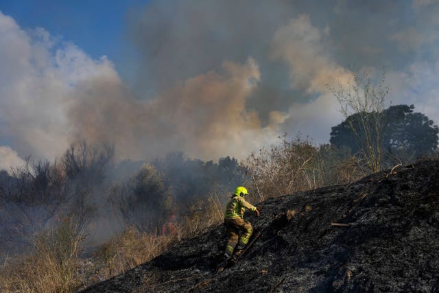 Firefighter walks up a scorched hillside