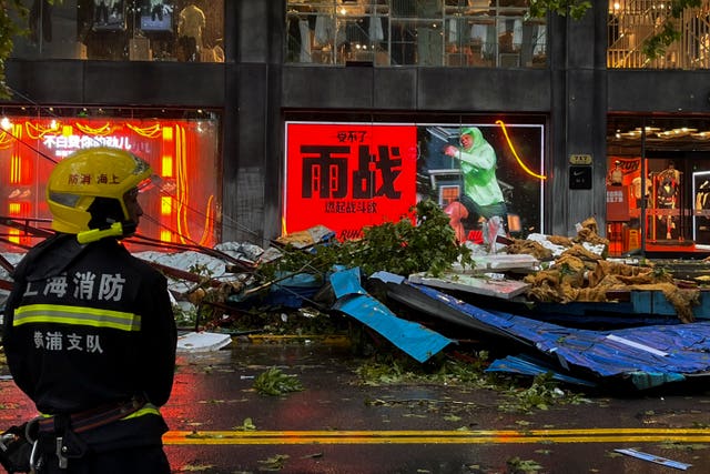 A firefighter stands near debris on a business street  in Shanghai, China, in the aftermath of Typhoon Bebinca 