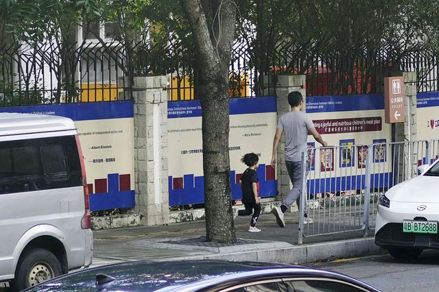 People walk past the Shenzhen Japanese School in Shenzhen, China after the attack