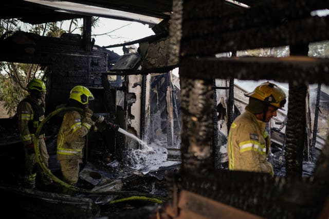 Israeli firefighters work at a house that was hit by a rocket fired from Lebanon