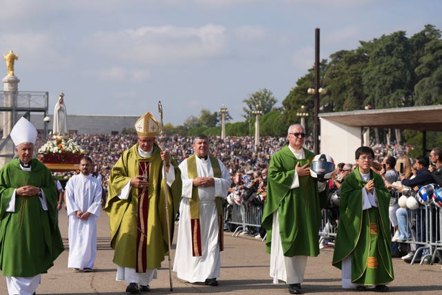 A priest carrying a Portuguese National Republican Guard motorcyclist helmet walks ahead of the Our Lady of Fatima statue in a procession starting the IX Pilgrimage of the Blessing of Helmets at the Roman Catholic holy shrine of Fatima to attend, in Fatima, Portugal 