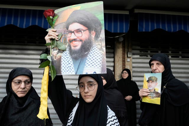 Hezbollah supporters carry pictures of Hezbollah commander Ibrahim Akil, right, and Hezbollah leader Hassan Nasrallah