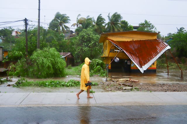 A person walks in the rain past a building after the passing of Hurricane John in Marquelia, Mexico