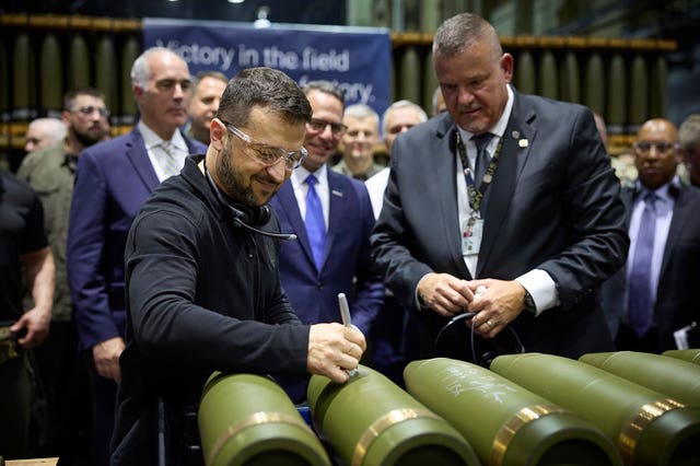 Volodymyr Zelensky is watched by Rich Hansen, the commander’s representative for the Scranton Army Ammunition Plant, while signing military ordnance