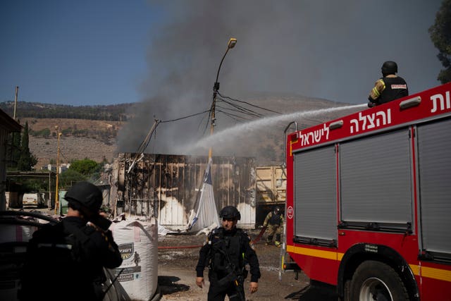 Firefighters work to extinguish a fire after a rocket hit a local municipality storage in Kiryat Shmona, northern Israel