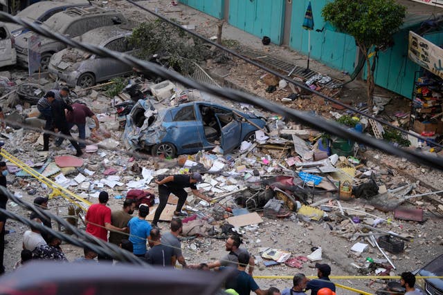 Residents check the site of an Israeli airstrike in Beirut’s southern suburbs