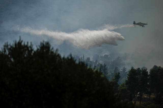 An Israeli firefighter plane flies over woodland in northern Israel