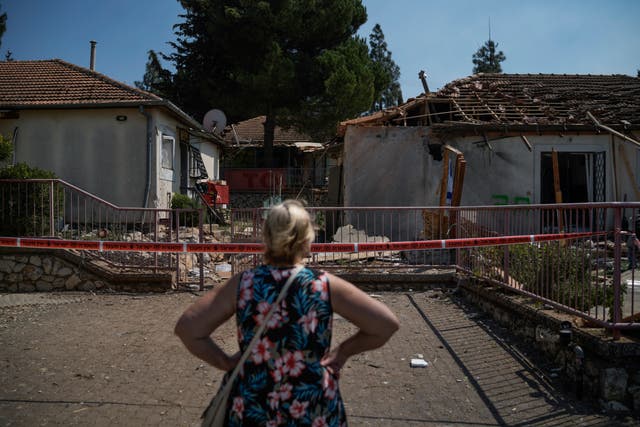 A woman looks at a damaged house that was hit by a rocket fired from Lebanon, near Safed, northern Israel