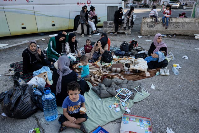 Families sit on the ground in Martyrs’ square after fleeing the Israeli airstrikes in Beirut’s southern suburbs