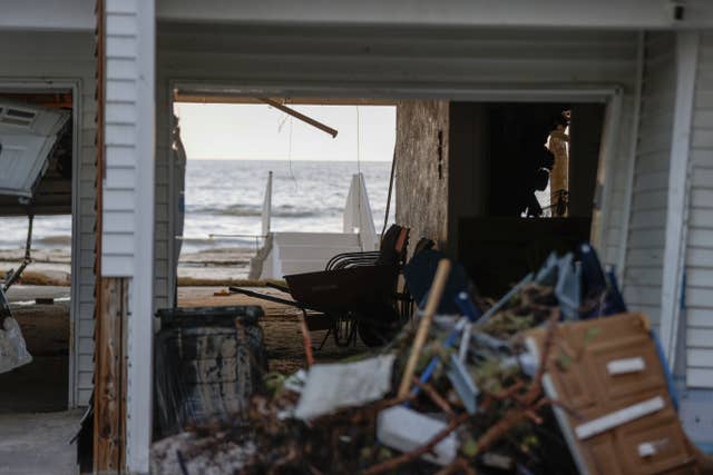 The sun shines through a hole in a building after storm surge from Hurricane Helene sent tons of sand into homes