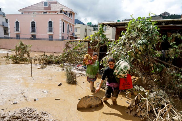 Women walk with their belongings in the mud in Kathmandu 