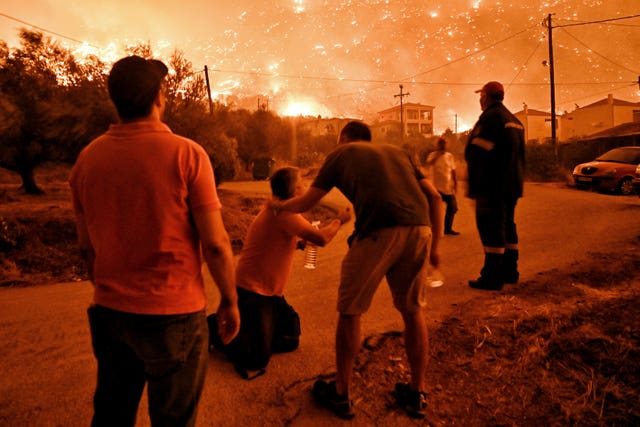 A resident reacts as a wildfire approaches the village of Ano Loutro