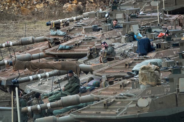 Israeli soldiers work on tanks in a staging area in northern Israel near the Lebanon border